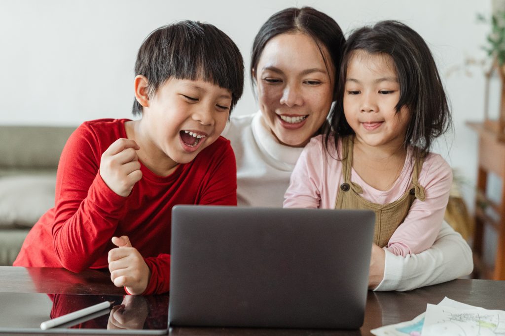 A chinese mother with her kids looking at laptop screen