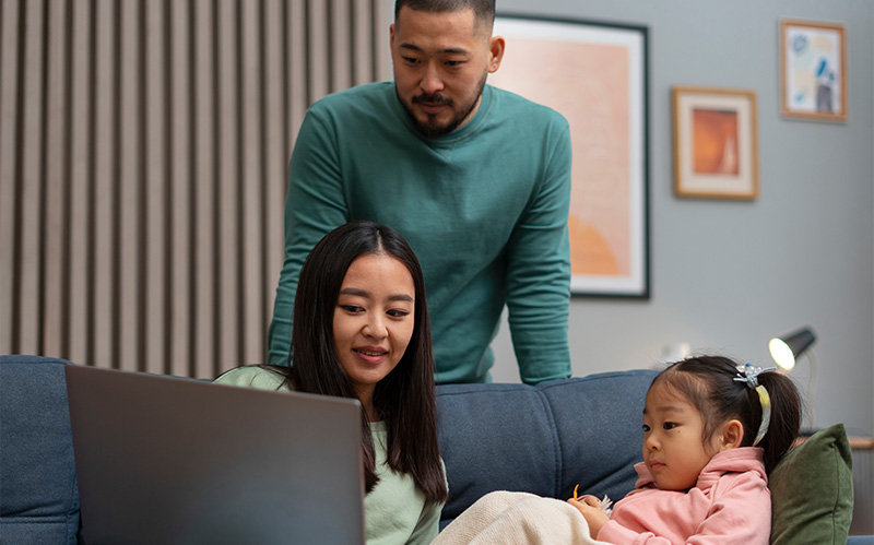 A mother and father sitting on a sofa with their young daughter