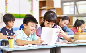 A young boy and girl sitting together in a classroom